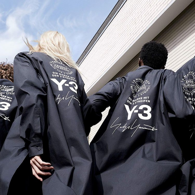 Y-3 adidas by Yohji Yamamoto brand banner image of two persons wearing long black jackets with backprints