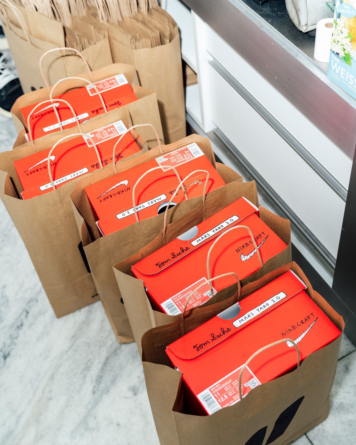 RECAP: Tom Sachs x Nike Mars Yard 3.0. Multiple boxes with red labels on a marble surface