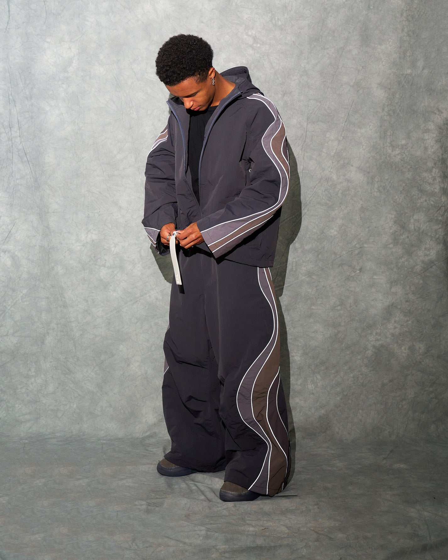 A man wearing ERL streetwear clothing and footwear in the same grey brown color palette