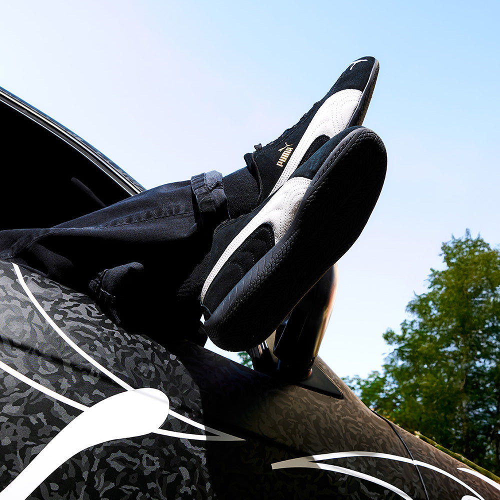 Someone wearing and displaying their Puma Speedcat sneakers outside of a car window