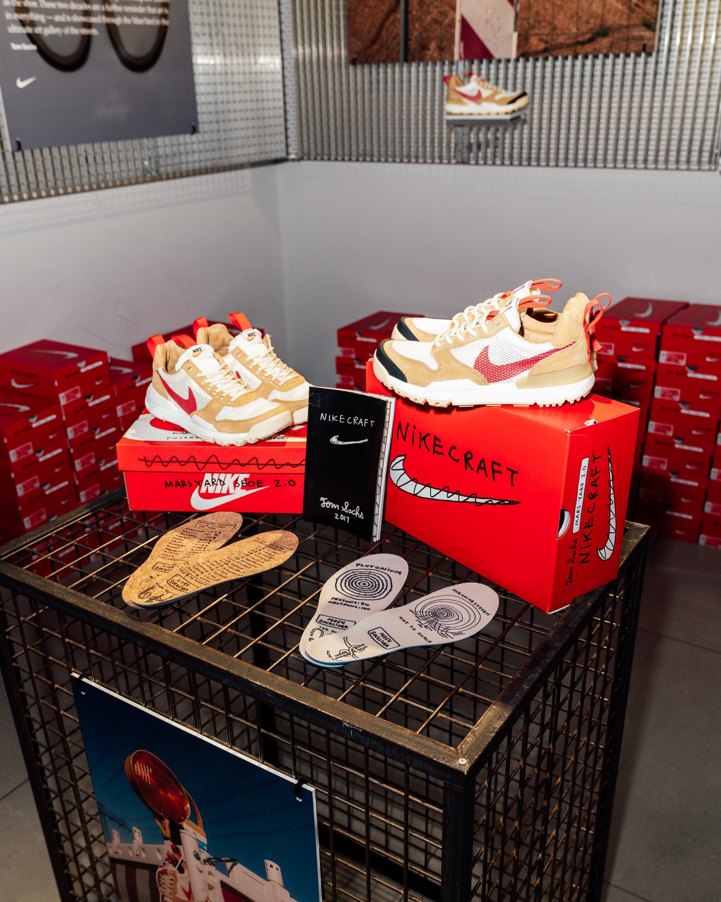 RECAP: Tom Sachs x Nike Mars Yard 3.0. Display of Nike sneakers and boxes on a metal crate with red shoe boxes in the background.