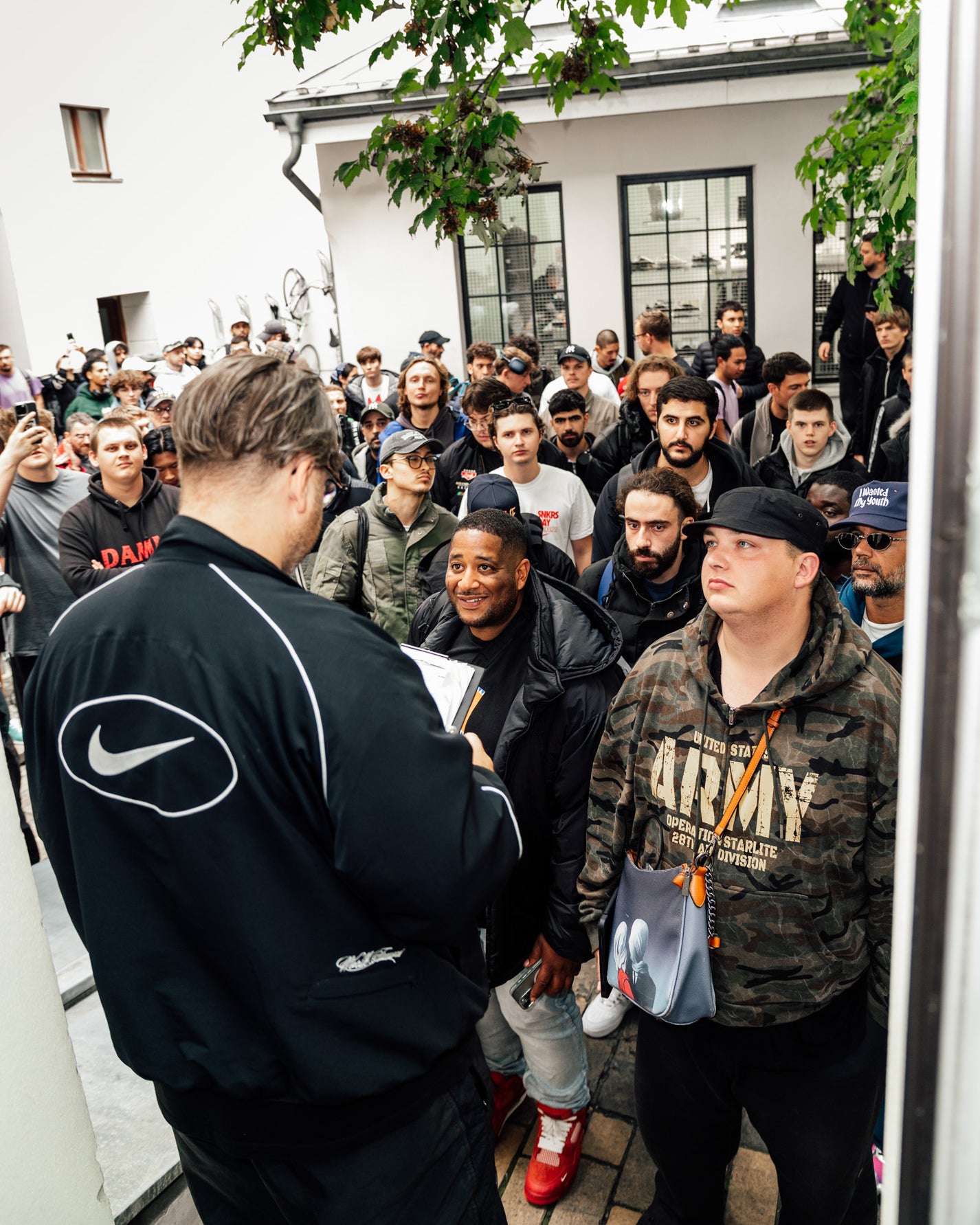 Group of people gathered outside a building with a person in a Nike jacket interacting with them. RECAP: Tom Sachs x Nike Mars Yard 3.0