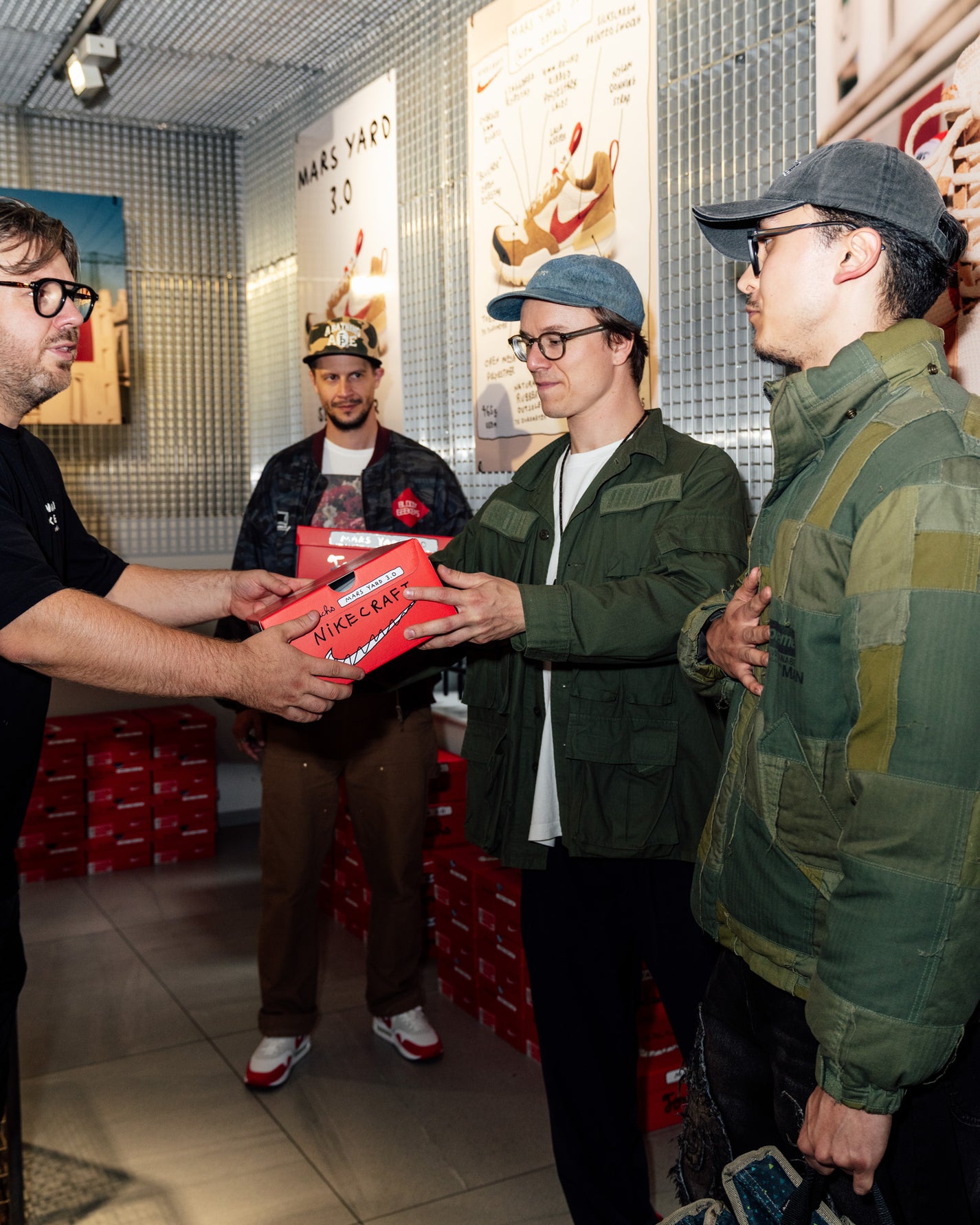 RECAP: Tom Sachs x Nike Mars Yard 3.0. Person receiving a red box from another person in a store setting.