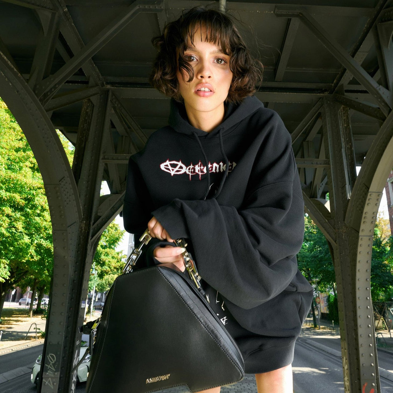 Women standing under brindge wearing wide black hoodie with print