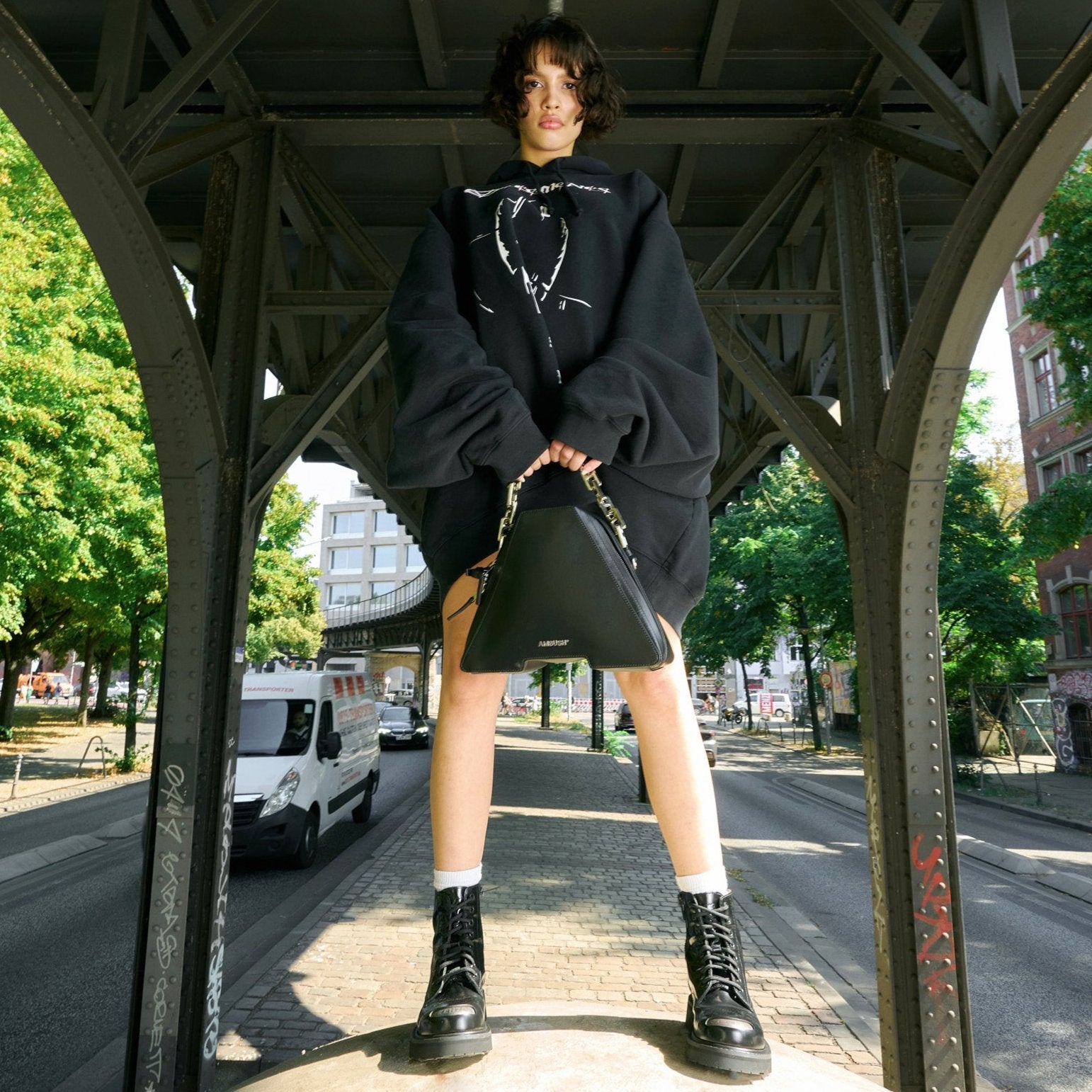 Women standing under brindge wearing wide black hoodie with print