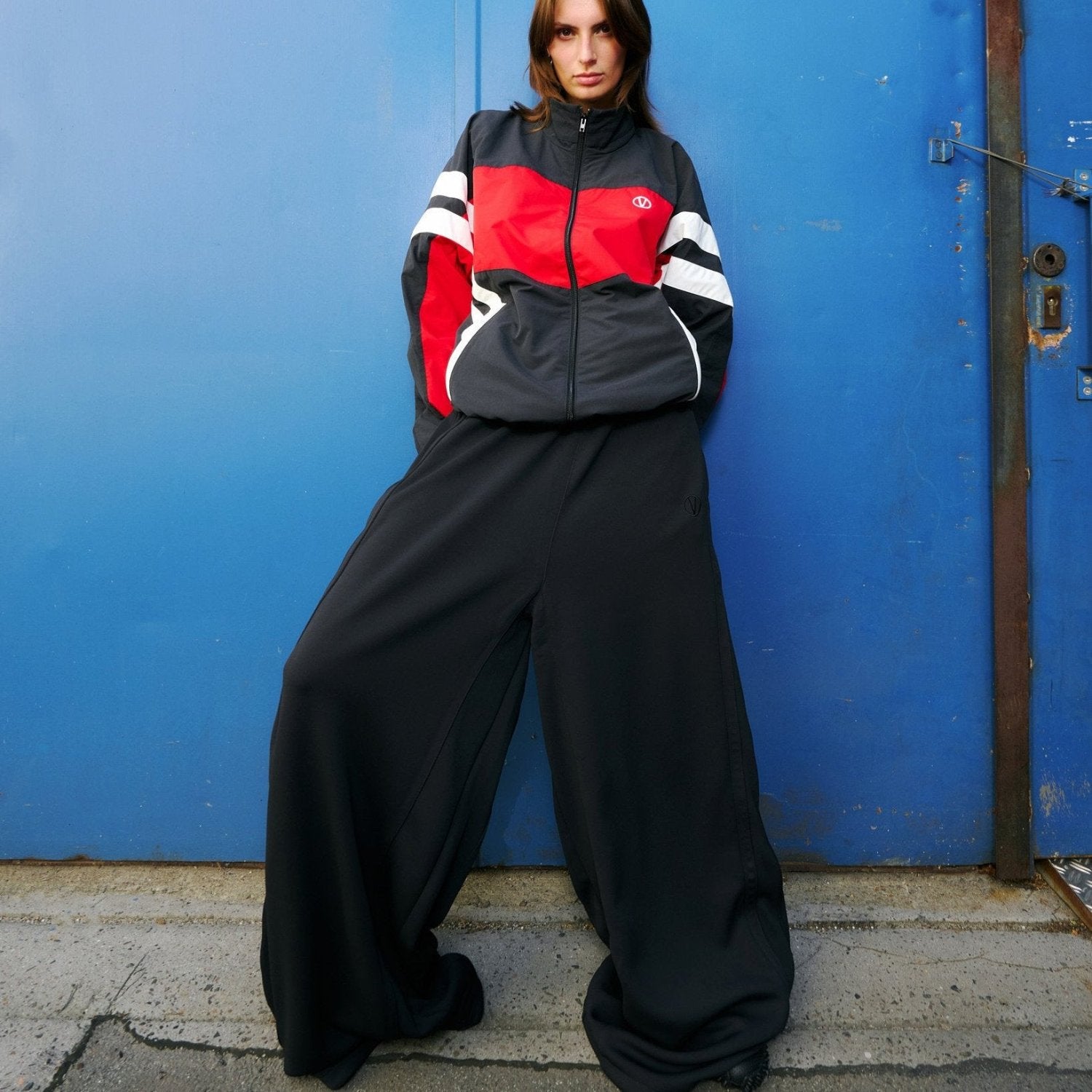 woman wearing wide black track pants and a black, red and white track jacket by vetements