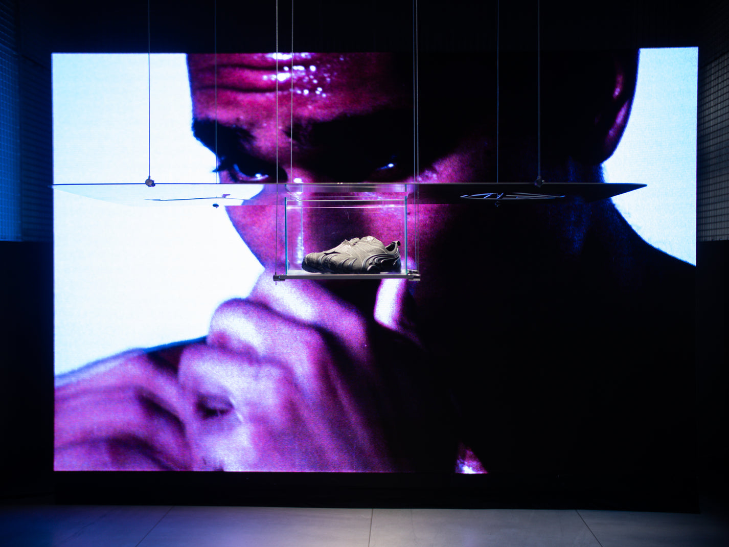 Puma x Non Faith Studios Event Recap. Close-up of a shoe displayed under a glass cover with a person's face in the background.